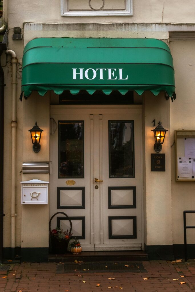 pexels photo 35129031 35129031 Cozy hotel entrance with a green awning and warm lanterns, inviting ambiance.